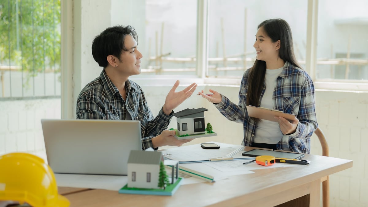 Professional contractors reviewing architectural plans with homeowners